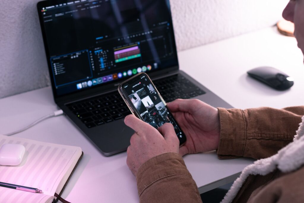 Person editing social media content on a laptop and smartphone